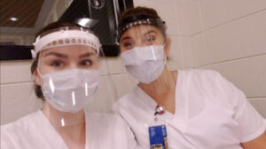 Two student nurses posing for a picture with scrubs and protective face coverings