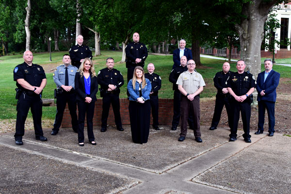 Students of Reinhard'ts ExCL program stand sociall distanced in the Echo Garden wearing law enforcement uniforms.