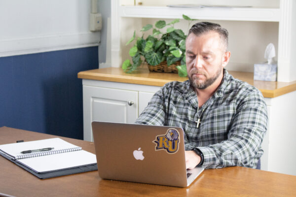 Online student Brian DeWitt typing on a laptop