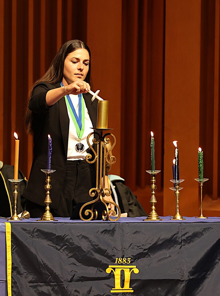 student lighting an Alpha Chi candle